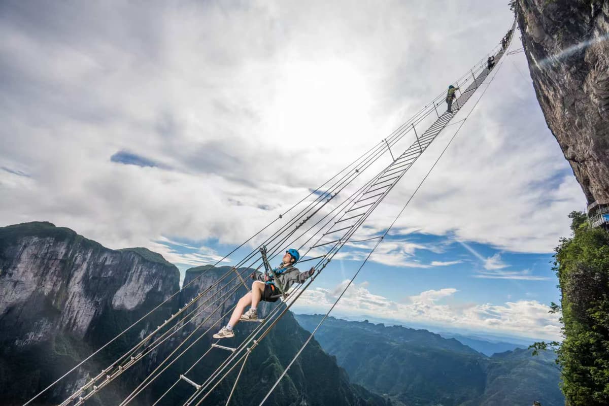 Leo Chang climbing a sky ladder high above the mountains